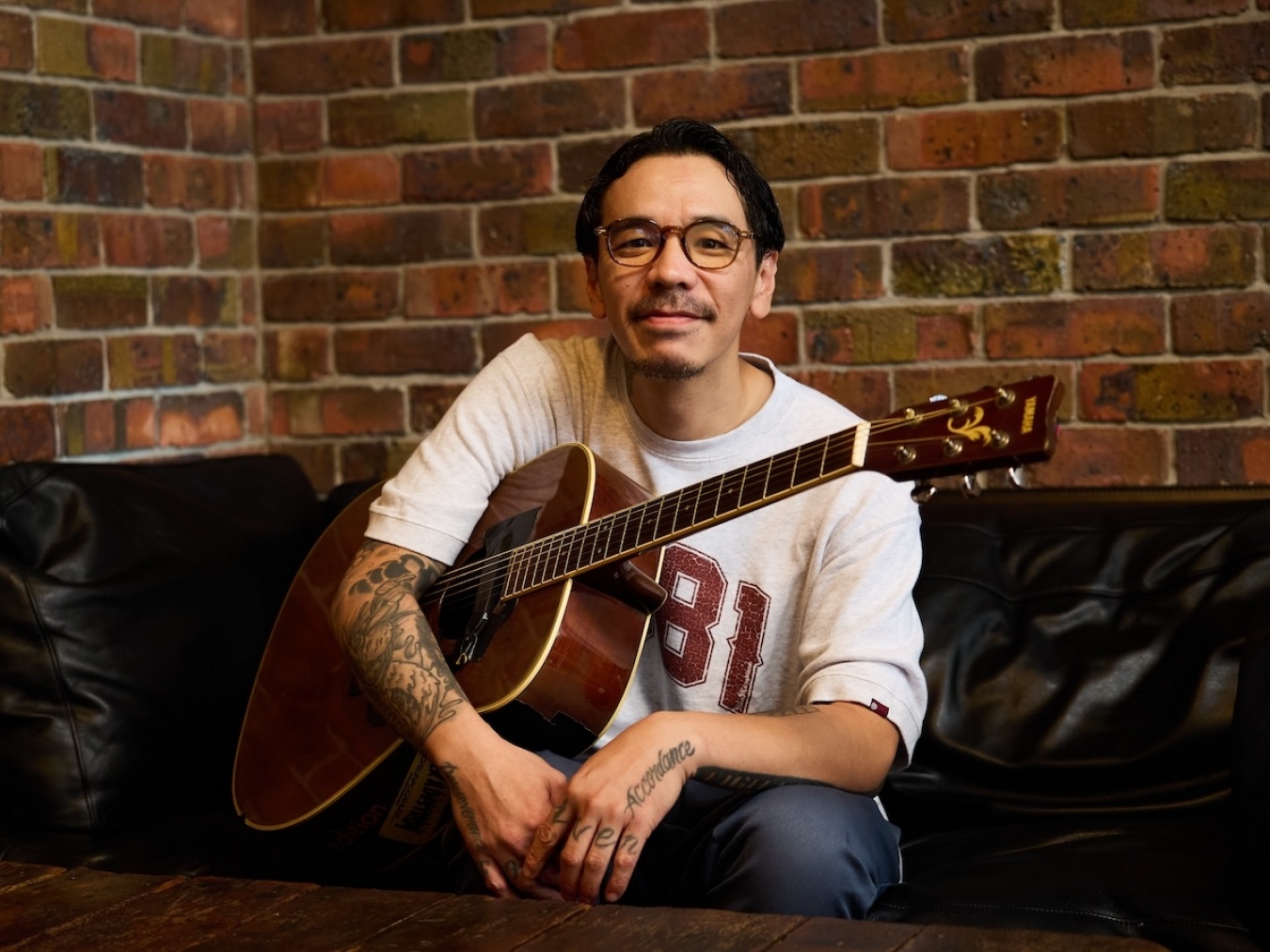 愛用のギターを抱える鉄井さん。