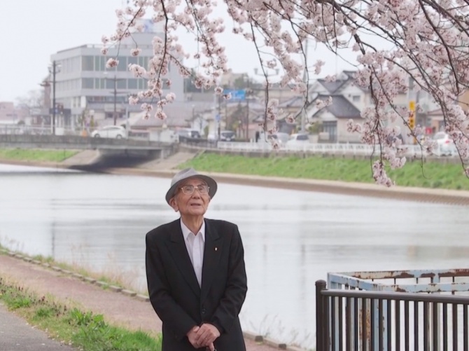 映画のオフショットから。美しい桜並木の下を歩く井山さん。Photo by いでは堂
